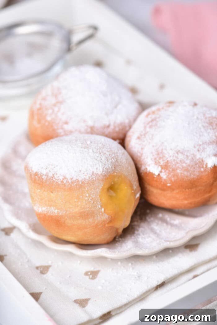 Zesty Lemon Burst Doughnuts 6 Close-up of three lemon-filled donut holes dusted with powdered sugar, showcasing the creamy lemon curd peeking out.