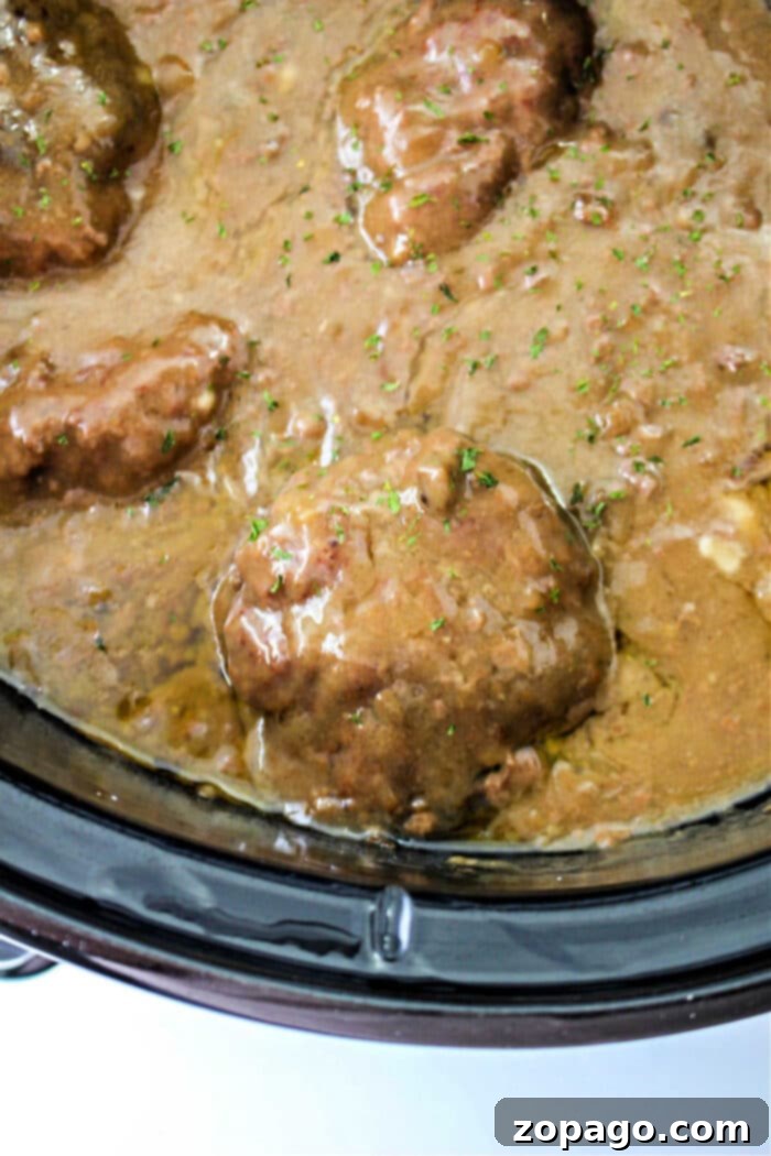 Minced Steak Symphony 5 Savor the aroma of chopped steak simmering in rich brown gravy inside a slow cooker, reminiscent of a classic chopped steak recipe.
