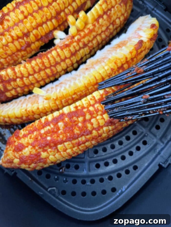 Addictive Crispy Corn Ribs 5 Vibrantly seasoned corn on the cob ribs, sizzling to perfection in a sleek black air fryer basket, embodying a delicious corn ribs recipe.