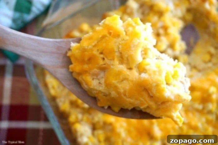 The best cream corn casserole recipe, made with Ritz crackers, Jiffy cornbread mix, and plenty of cheese, serves as an easy, fabulous side dish. A warm, golden cream corn casserole with cheese, scooped onto a white plate, showcasing its fluffy texture and rich, comforting appeal.