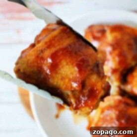 A close-up of an Instant Pot BBQ chicken thigh, perfectly grilled and held by tongs over a plate, with more glazed pieces tempting in the background.