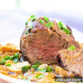 Sliced eye of round roast perfectly prepared garnished with herbs and served alongside sautéed mushrooms and onions.