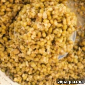 A pot filled with perfectly cooked mung beans, with a ladle elegantly scooping some from the center—a glimpse into mastering how to cook mung beans.