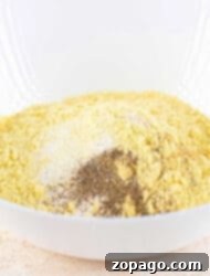 A white bowl brimming with a blend perfect for fish fry, combining cornmeal, pepper, and flour.