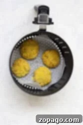 Crispy Cod Cakes 8 Four uncooked cod fish cakes rest in an air fryer basket lined with parchment paper.