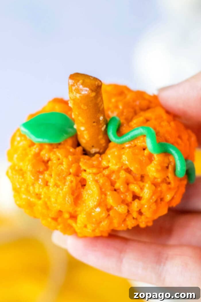 Crispy Autumn Pumpkin Bites 2 Halloween Rice Krispie Treats shaped like vibrant orange pumpkins, ready for a spooky celebration.