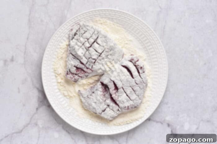 Tenderized Venison Steak 4 Two raw, flour-dusted deer steaks rest on a white plate, ready for pan-frying to become delicious venison cube steak.