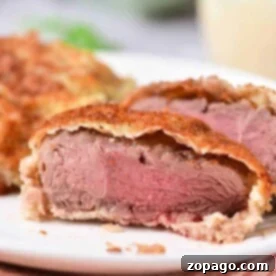 Close-up of a sliced venison cube steak, revealing tender pink wrapped in flaky pastry