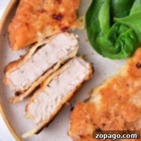 Close-up of succulent pork cube steak fried to perfection, served on a plate with fresh spinach leaves.