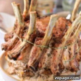 A beautifully cooked crown roast of pork, tied elegantly with string, graces a white plate—a feast-worthy centerpiece from the finest crown roast of pork recipe.