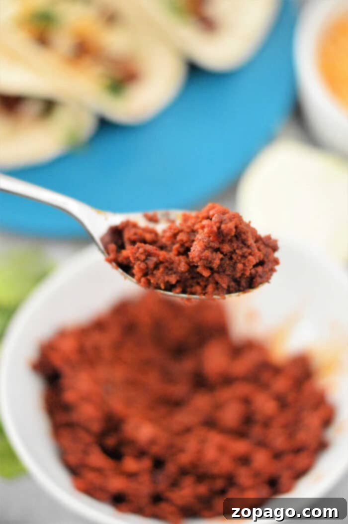 Close-up of a spoonful of perfectly seasoned chorizo over a bowl, ready for taco assembly.
