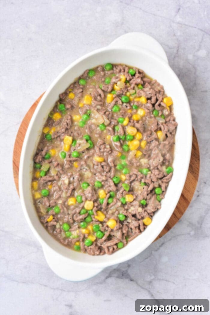 Hearty Ground Beef Hash Brown Bake 4 A large baking dish filled with a golden-brown ground beef hash brown casserole, topped with melted cheese.