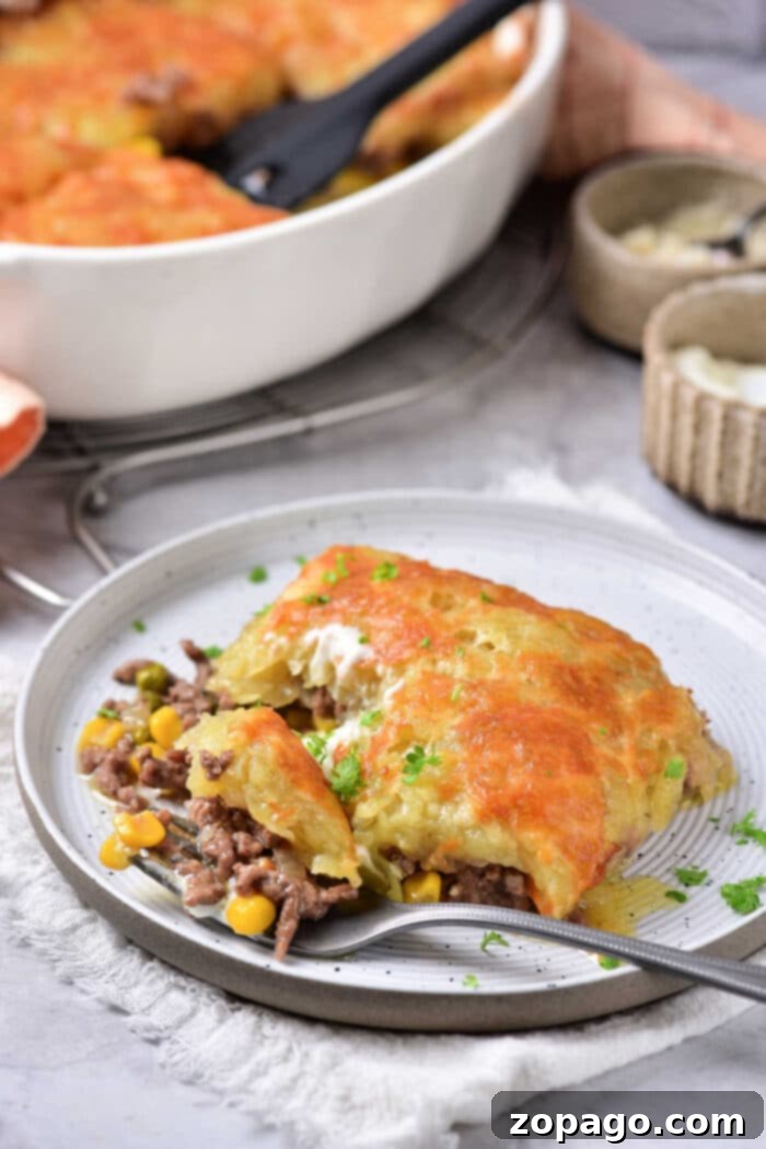 Hearty Ground Beef Hash Brown Bake 6 A generous, perfectly portioned slice of ground beef hash brown casserole, showcasing melted cheese, vegetables, and savory ingredients, with the baking dish in the background.
