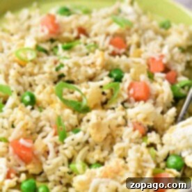 Savory Egg and Pea Fried Rice 7 A plate of egg fried rice with peas, chopped tomatoes, and green onions showcases a delicious take on how to make egg fried rice at home.
