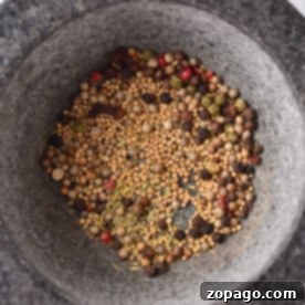 A variety of whole spices in a stone mortar, perfect for crafting your own corned beef spice recipe.