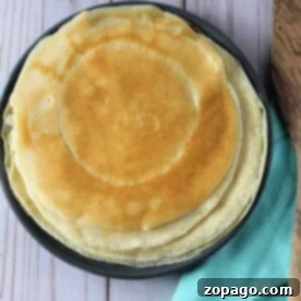 Transform Pancake Mix into Perfect Crepes 7 A stack of round, golden crepes sits invitingly on a plate, with a teal napkin beside it, showcasing just how easy it is to make crepes using pancake mix.