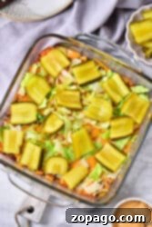 Big Mac Bake 10 Big Mac Casserole topped with sliced pickles and lettuce in a glass baking dish.