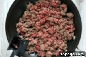 Big Mac Bake 6 Ground beef being browned in a black skillet with a black spatula resting on the side—perfect for an easy sloppy joe recipe 3 ingredients or less.