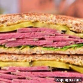 The Ultimate Corned Beef Stack 6 Close-up of a delectable corned beef sandwich recipe, featuring tender slices, crisp pickles, and fresh lettuce nestled between hearty whole grain bread.