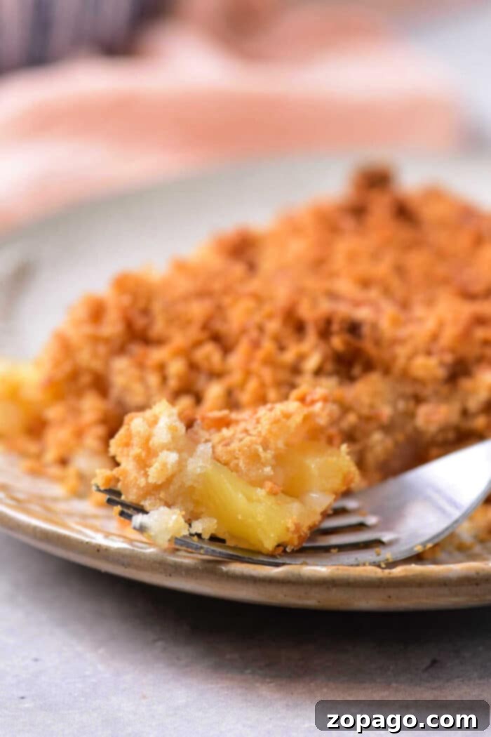 Tropical Pineapple Delight 2 Close-up of a fork with a bite of golden-brown pineapple casserole, highlighting its crumbly streusel topping and soft, cheesy pineapple filling, ready to be enjoyed as a Southern dessert or side.