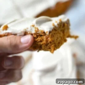 Close-up of a hand holding pumpkin bars made with cake mix, and more cake pieces in the background.