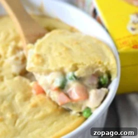 Easy Chicken Cobbler Bake with Bisquick 8 A creamy chicken cobbler pot pie with a slice being served, revealing tender vegetables beneath its golden crust.