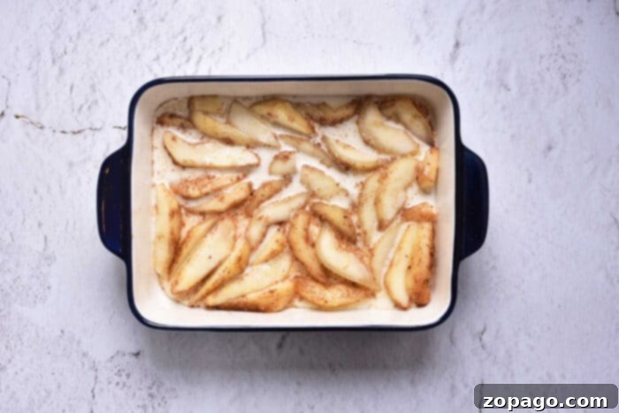 Caramelized Pear Crown Cake 4 A slice of homemade fresh pear cake, revealing layers of tender cake and cooked pear, served on a white plate with a fork.