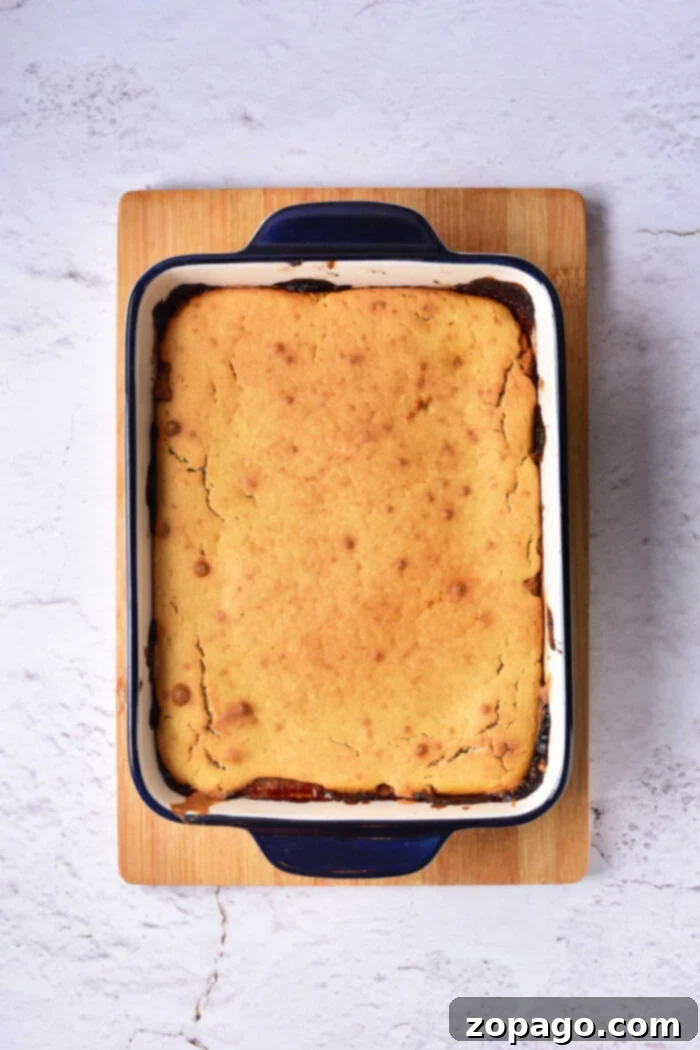 Caramelized Pear Crown Cake 6 A golden-brown baked Pear Upside Down Cake, still warm in its rectangular blue and white baking dish, set on a rustic wooden board, ready to be served.