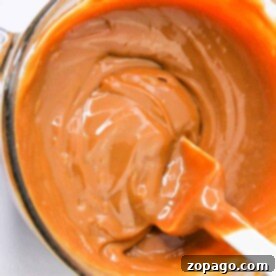 Slow Cooker Dulce de Leche 6 A pot of creamy caramel with a spatula, showing a smooth, rich texture—a delightful result when you know how to make caramel with condensed milk.