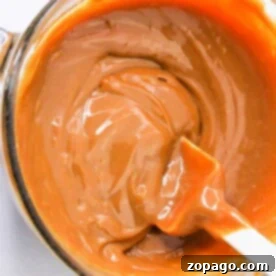 A pot of creamy caramel with a spatula, showing a smooth, rich texture—a delightful result when you know how to make caramel with condensed milk.