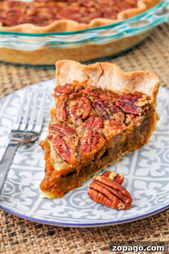 Ultimate Pumpkin Pecan Pie 6 A generous slice of Homemade Pumpkin Pecan Pie, ready to be served, highlighting the distinct, flavorful layers of pumpkin and pecan.