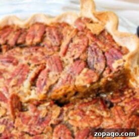 Ultimate Pumpkin Pecan Pie 7 Close-up of a pecan pie with a slice being lifted, revealing its flaky crust and nutty, caramelized filling. This delightful treat brings to mind an easy pumpkin pie with pecan topping—a fusion of flavors perfect for any festive occasion.
