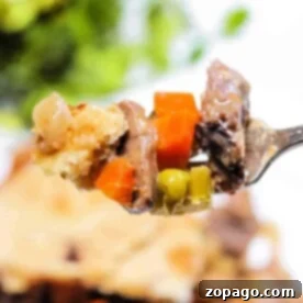 Hearty Steak Pot Pie 6 Close-up of a fork holding a bite of leftover steak pot pie with carrots, peas, and golden crust.