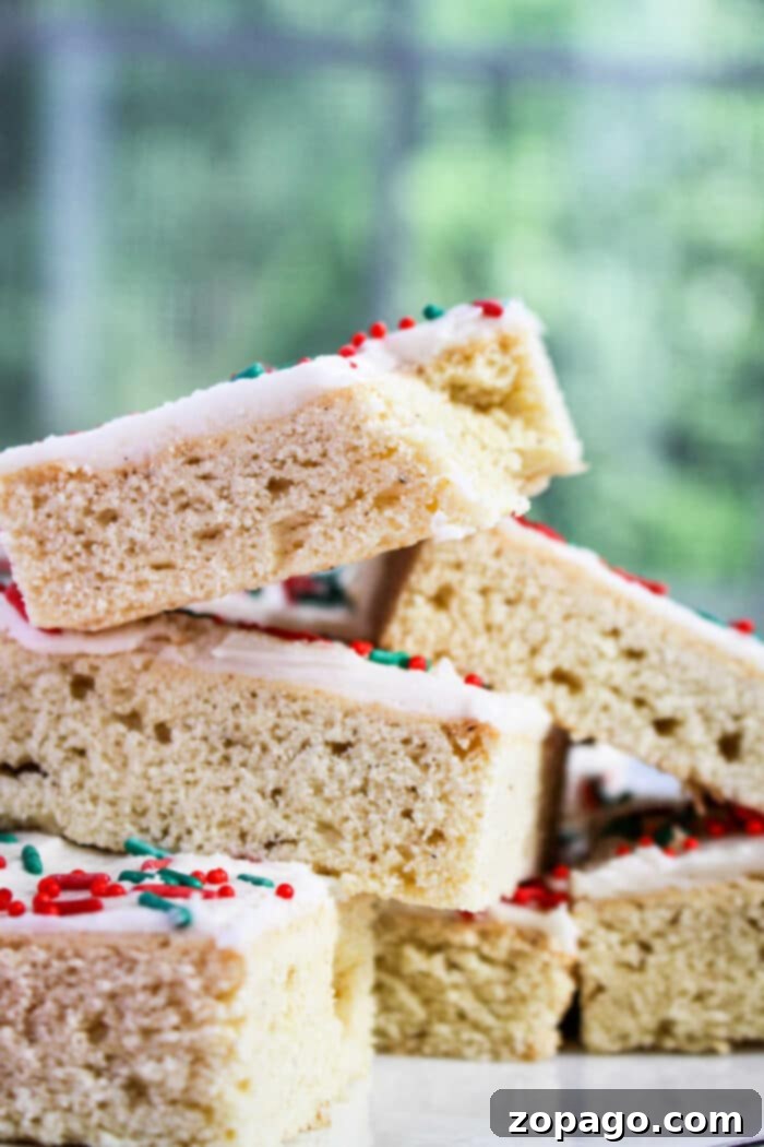 Easy Sugar Cookie Bars 7 Close-up of frosted cookie bar squares stacked like festive Christmas bar cookies, topped with red and green sprinkles.