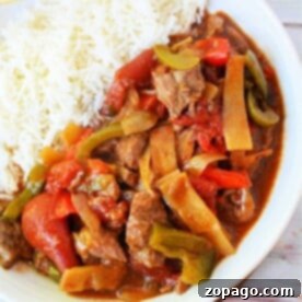 Plate of slow cooker pepper steak with bell peppers and rice, served with chopsticks.