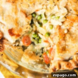Creamy Chicken Pot Pie Recipe 6 Close-up of a golden-brown chicken pot pie with a slice removed, revealing peas, carrots, and creamy filling inside—perfectly capturing the essence of a classic recipe made with cream of chicken soup.