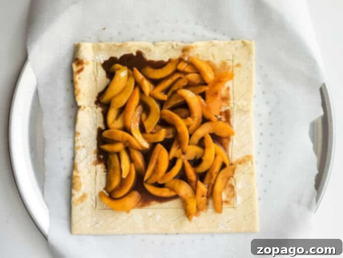 Golden Flaky Tart 5 Freshly sliced peaches arranged on a sheet of puff pastry, ready for baking.