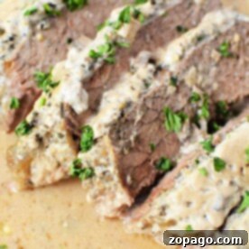 Slow Cooker London Broil 7 Enjoy tender London Broil for the Slow Cooker, featuring sliced beef topped with a creamy sauce and garnished with chopped parsley.