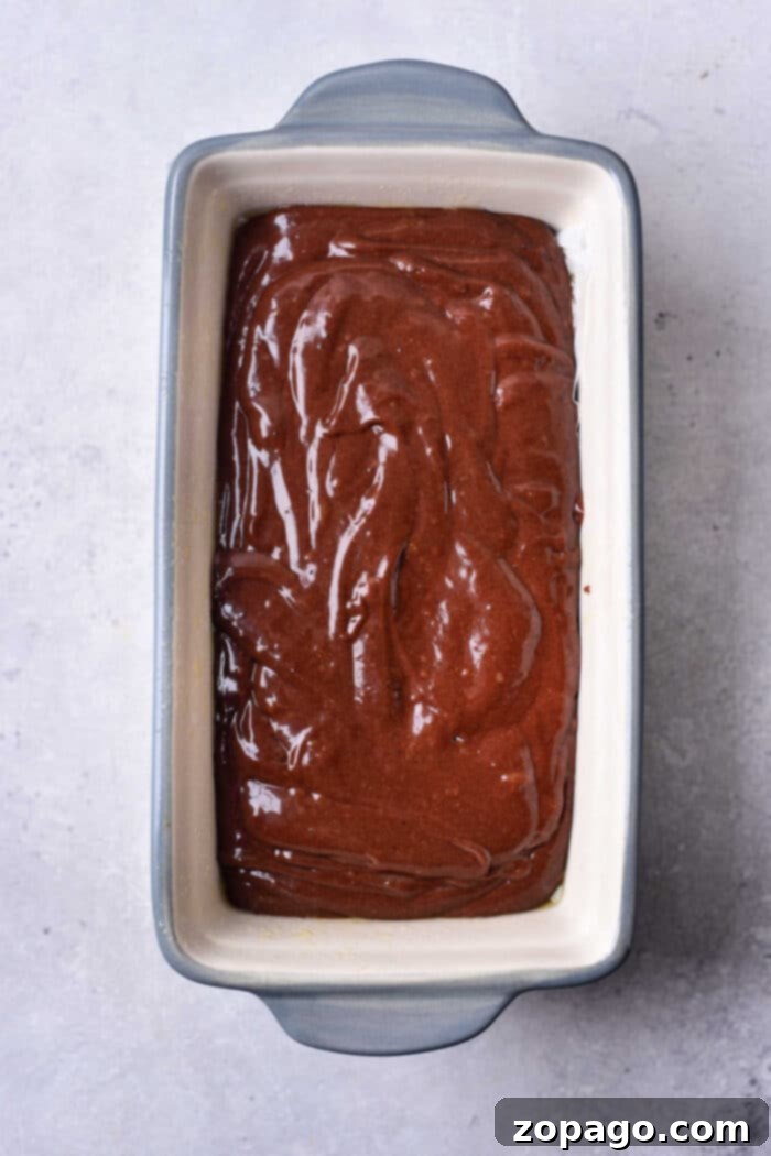 Molten Chocolate Brownie Loaf 4 A rectangular baking dish filled with smooth, uncooked Brownie Bread batter rests on a light surface, promising a rich chocolate treat.