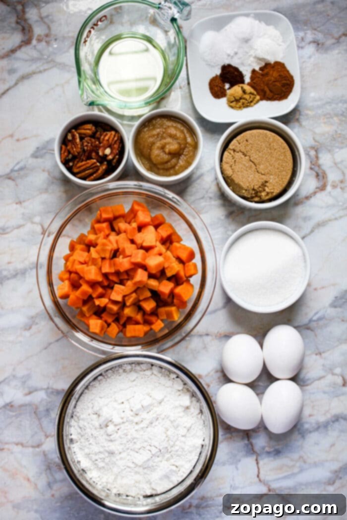 Moist Sweet Potato Cake 3 Baking ingredients for Sweet Potato Cake: eggs, flour, sugar, sweet potatoes, pecans, oil, applesauce, and spices on a marble surface.
