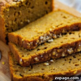 Maple Pumpkin Bread, sliced and adorned with oats, is elegantly arranged on a wooden board.