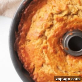 A freshly baked bundt cake in a round pan on a light surface beckons with its golden crust, much like knowing how to tell if banana bread is done—by ensuring it's perfectly baked throughout.