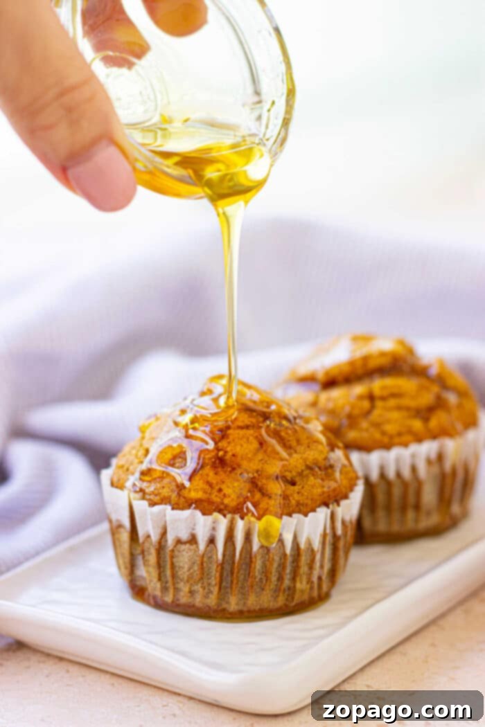 Easy Gluten-Free Pumpkin Muffins 6 A stack of warm gluten-free pumpkin muffins on a wooden board.