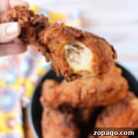 Perfect Oil Temp for Crispy Fried Chicken 8 A hand grips a crispy fried chicken drumstick with a bite missing, hovering tantalizingly above a bowl brimming with more golden pieces. Ever wonder how hot should oil be for fried chicken? The perfect temperature ensures that irresistible crunch.