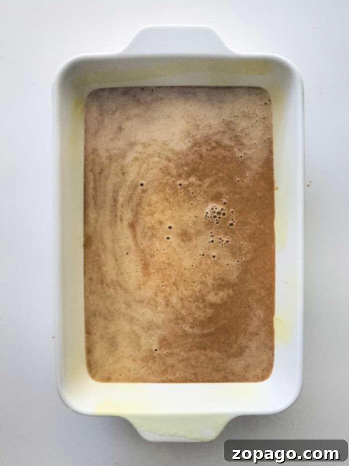 Spiced Sweet Potato Dump Cake 3 White rectangular baking dish with a rich caramel glaze on a Sweet Potato Dump Cake, viewed from above, highlighting the golden brown pecan topping.