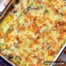 A delightful frozen green bean casserole topped with melted cheese and crispy fried onions, served in a blue rectangular dish.