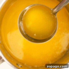 Ladle scooping golden melted butter from a saucepan, showcasing how to make liquid butter with ease.