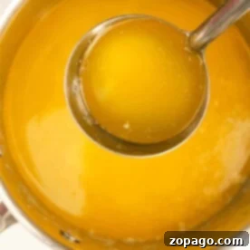 Pourable Perfection: Making Liquid Butter 7 Ladle scooping golden melted butter from a saucepan, showcasing how to make liquid butter with ease.