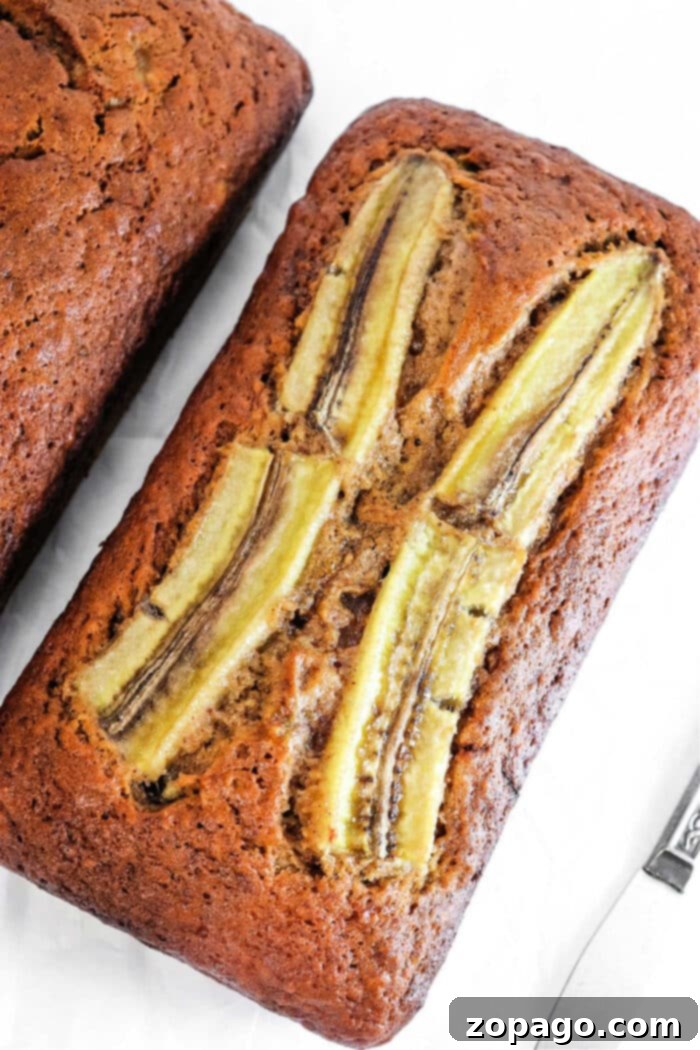 Moist No Butter Banana Bread 7 A freshly baked loaf of banana bread, baked without butter or oil, presented on a cooling rack with slices ready to be served.