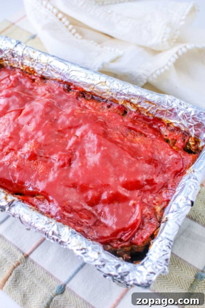 Quick and Easy Stuffing Meatloaf 6 Stove Top Stuffing Meatloaf covered in glaze rests in a foil-lined pan on a plaid cloth.